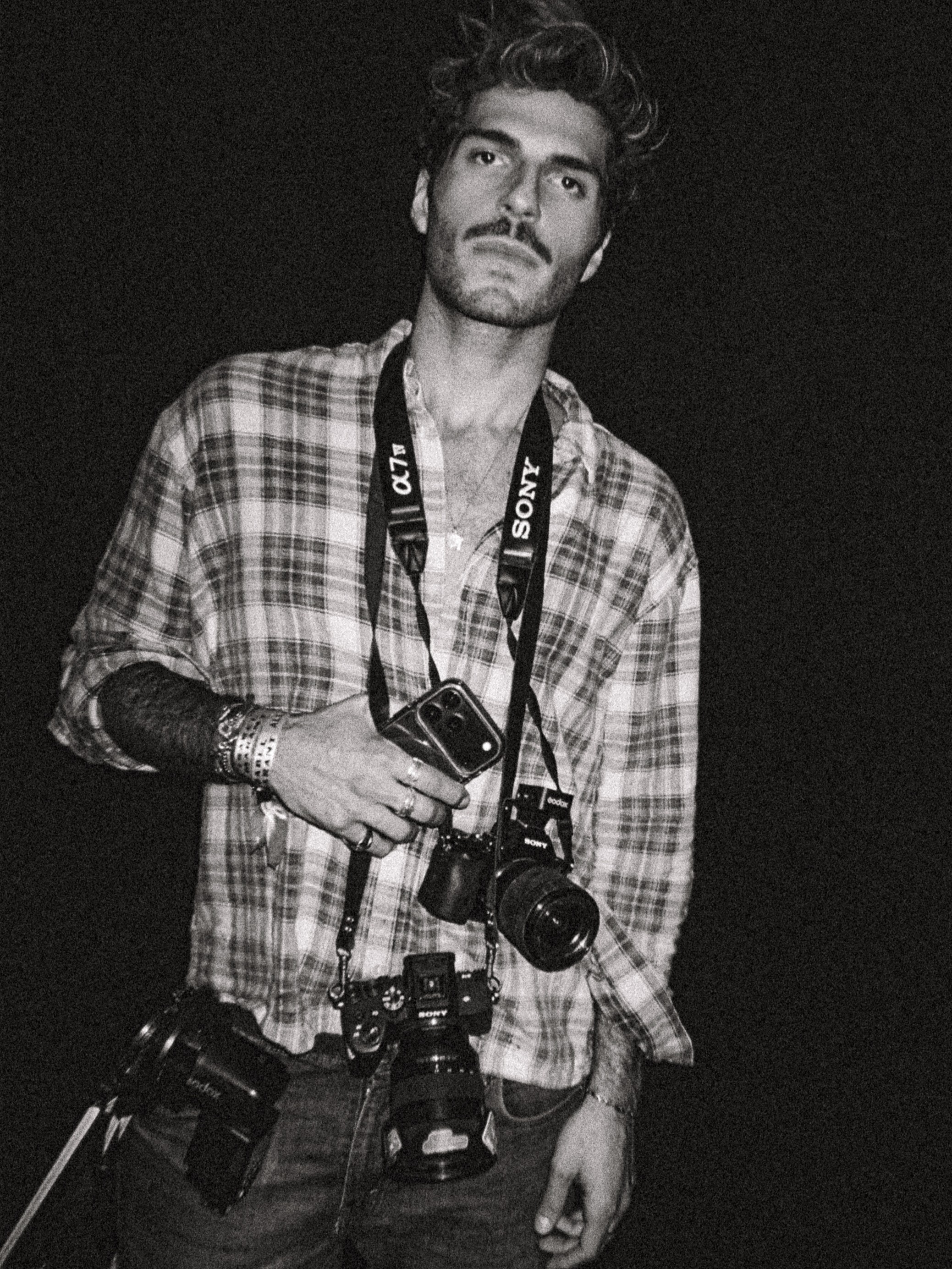 Gabryel Sallehount holding cameras in a black-and-white portrait